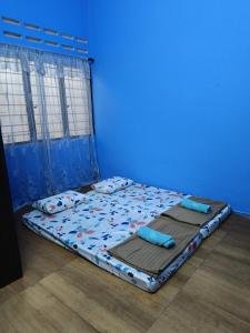 a bed in a blue room with two pillows on it at Lin's Homestay in Port Dickson