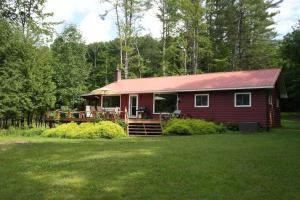 a red house with a red roof on a yard at Mary Lake Sunset Lodge in Port Sydney