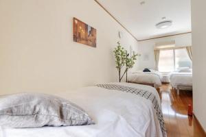 a white bedroom with two beds and a window at Abiko Stay in Osaka Namba in Osaka +19 photos