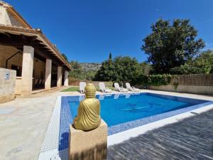 a pool with chairs and a statue next to a house at Villa Lara in Sa Pobla