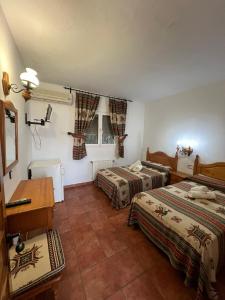 a room with two beds and a desk in it at Pensión Xiquena in Fiñana