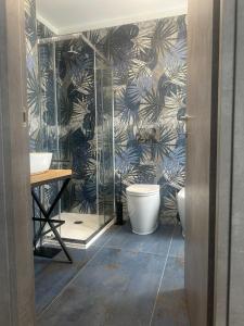 a bathroom with a toilet and a wall with palm leaves at Appartamento La Ginestra in Gozzano
