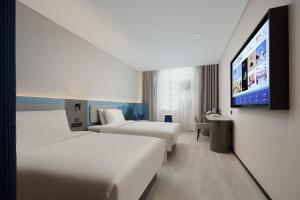 um quarto de hotel com duas camas e uma TV de tela plana em Atour Light Hotel Shanghai Minhang Jingxi Road em Xangai
