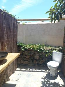 Un inodoro situado en un patio junto a un muro de piedra. en Studio with pool garden and open roof bathroom, en Lajares
