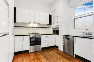 墨尔本Large 3 Bed Art Deco Apartment in Camberwell的厨房配有白色橱柜和炉灶烤箱