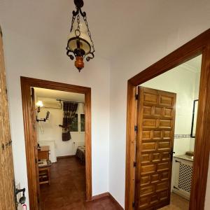 a hallway with a wooden door and a chandelier at Pensión Xiquena in Fiñana