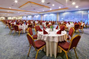 um salão de banquetes com mesas brancas e cadeiras com guardanapos vermelhos em Pam Thermal Hotel Clinic & Spa em Pamukkale