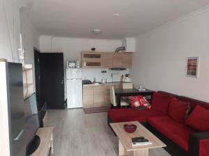 a living room with a red couch and a kitchen at Studio Sarafovo in Burgas