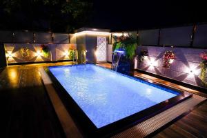 a large swimming pool with lights in a house at BluStone By The StayCationer in Malavli +6 photos