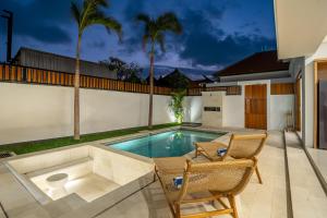 a swimming pool in a backyard with two chairs and a table at Sofia 1- Luxury Retreat - Brand New 2BR Villa with Private Pool in Canggu