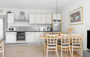 a kitchen with white cabinets and a table and chairs at Gudhjem Søpark Lejl 42 in Gudhjem +17 photos