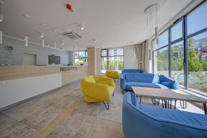 a waiting room with blue chairs and a table and a yellow chair at Cinema Hotel in Primorsko