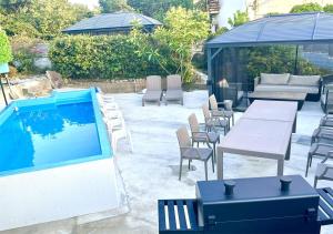 Un patio con mesas y sillas y una piscina. en 雨でも炭火BBQ可!プール付き!Max12名!駐車場2台!千畳敷三段壁近く, en Shirahama