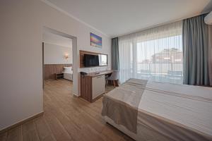 a hotel room with a bed and a desk and a television at Cinema Hotel in Primorsko +71 photos
