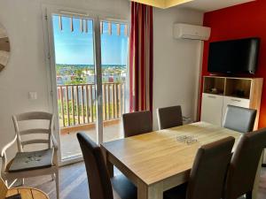 a dining room with a table and chairs and a balcony at Cosy plage - Appt climatisé avec piscine partagée in Sète