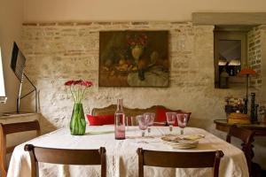 a dining room table with a vase of flowers and a painting at La Ferme de Marie Eugénie in Bruailles