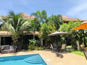 a cat laying next to a house with a swimming pool at Aurora Resort in Ban Pru Yai