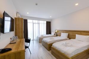 a hotel room with two beds and a desk at Aqua Batumi Hotel & Apartments in Batumi