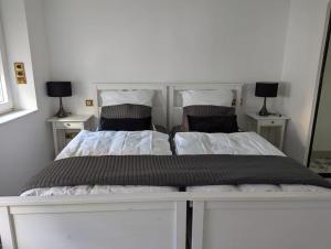 two beds in a white bedroom with two lamps at Stadtnahe Wohnung direkt am Dom in Worms