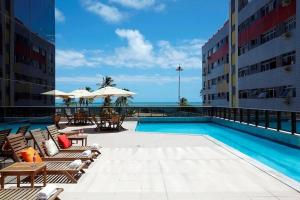 Una piscina con sillas y sombrillas al lado de un edificio. en Recife Pina Boa Viagem Beach, en Recife