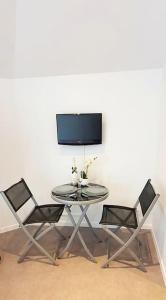 een tafel met twee stoelen en een tv aan de muur bij Chic & Contemporain in Vierzon