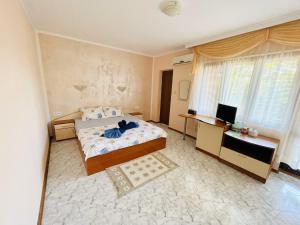 a bedroom with a bed and a desk and a television at Kastela Guest House in Chernomorets