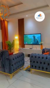 a living room with two blue couches and a flat screen tv at Merkur Apparts in Yaoundé