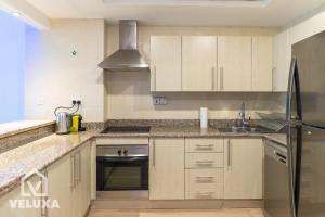 a kitchen with wooden cabinets and a sink and a refrigerator at Veluxa - Renovated! La Maison des Artist in Dubai