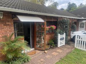 una casa di mattoni con una tenda da sole e una staccionata bianca di Tranquil Gardens a Pietermaritzburg