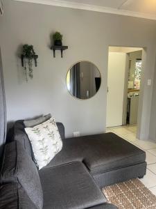 un soggiorno con un divano e uno specchio di Tranquil Gardens a Pietermaritzburg