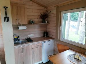 a kitchen in a log cabin with a table and a window at Jaučio apartamentai in Leliūnai