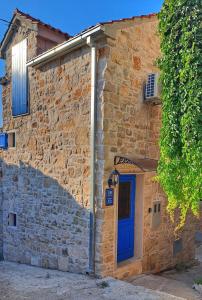a brick building with a blue door on it at Domus Lapidea in Postira