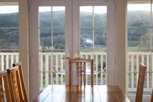 a dining room table in front of a window at BCC Loch Ness Cottages in Drumnadrochit