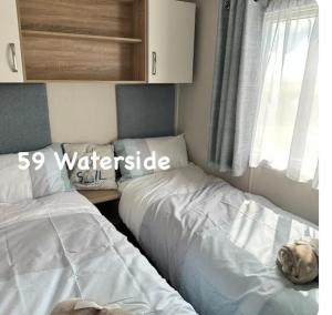a bedroom with two beds next to a window at Waterside 59 in Chwilog