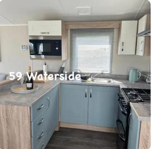 a kitchen with a sink and a stove top oven at Waterside 59 in Chwilog