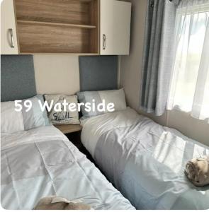 a bedroom with two beds next to a window at Waterside 59 in Chwilog +11 photos