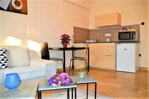 a living room with a white couch and a kitchen at Downtown- Családi Apartman in Győr