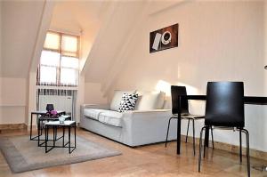 a living room with a white couch and black chairs at Downtown- Családi Apartman in Győr