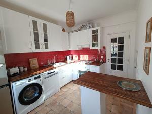a kitchen with white cabinets and a washing machine at Casa Flow and Glow in Santiago do Cacém