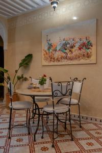 een tafel en stoelen in een kamer met een schilderij aan de muur bij Riad Dar Tuscia in Marrakesh