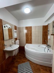a bathroom with a large white tub and a sink at Pensiunea Cezara in Bacău
