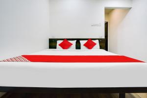 a white bed with red pillows in a room at Hotel O White Villa in Nagpur