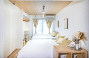 大阪市にあるルミエール天満のベッド2台とテーブルのある白い寝室