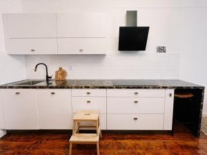 a kitchen with white cabinets and a sink and a stool at Cozy flat in Center in Maribor +6 photos