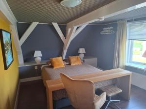 a bedroom with a bed with a desk and a chair at Het Burgemeestershuis in Barsingerhorn