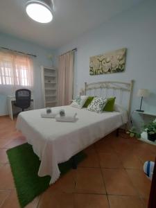 a bedroom with a large white bed with green pillows at Casa-Chalet Anabel in El Puerto de Santa María