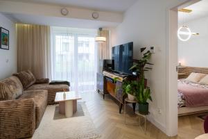 Charming Apartment in a green area- free parking في كراكوف: غرفة معيشة مع أريكة وسرير