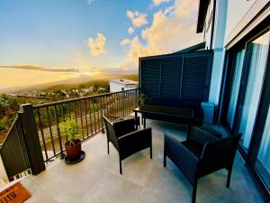 einen Balkon mit Stühlen und einem Tisch mit Blick auf den Strand in der Unterkunft Duplex Bellevue - Entre Mer et Montagne - Meublé Classé 3 Etoiles in Le Tampon