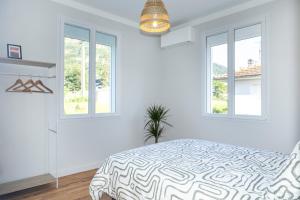 a white bedroom with a bed and two windows at Chez Barrau - Confort et charme au cœur de Lourdes in Aspin-en-Lavedan