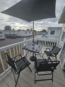 a table and chairs on a deck with an umbrella at Highfield Grange Holiday Park in Clacton-on-Sea